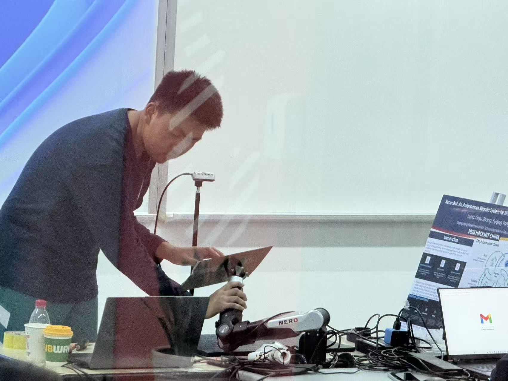 Team member using the calibration board with the robot and camera for coordinate alignment.