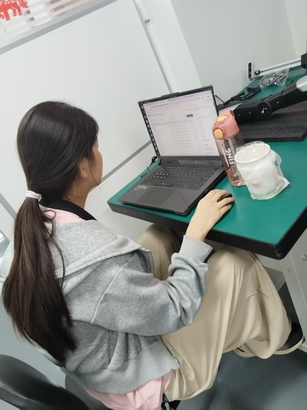 Team member preparing and uploading project materials beside the robot setup.